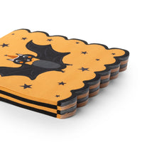 Stack of scalloped vintage Halloween paper napkins showing an orange napkin with a black bat in a party hat and scattered stars
