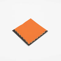 Single folded vintage Halloween cocktail napkin showing the pumpkin orange base and black-cream ric-rac edge detail.