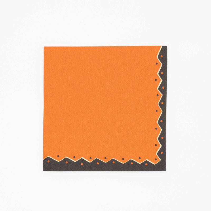 Vintage Halloween cocktail napkin in pumpkin orange with black and cream ric-rac dot detailing along the edges, flat view on white background.