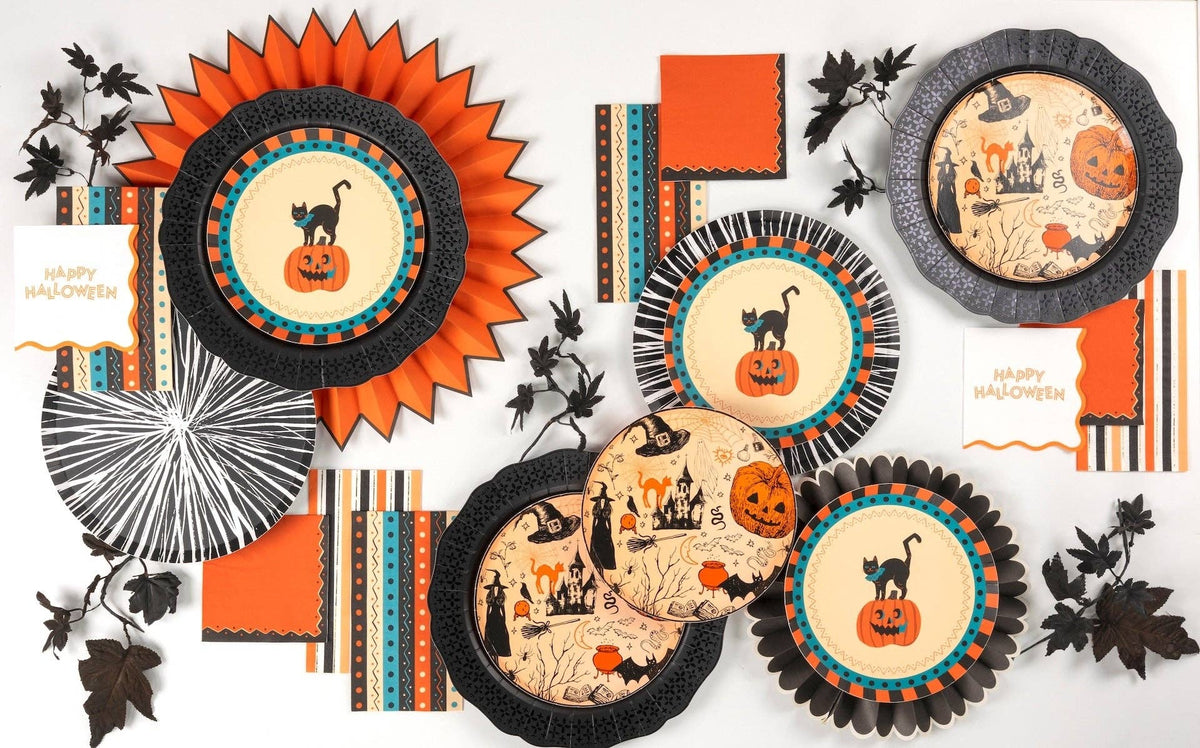 Flat lay of the vintage Halloween collection — cat plates, black rosette chargers, retro striped towels, paper fans, and orange napkins.