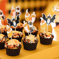 Vintage Halloween bat, owl, black cat, and pumpkin clown cupcake toppers in orange frosted cupcakes with orange and black sprinkles