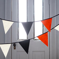 Close-up of black, orange and cream felt pennants strung on ribbon.