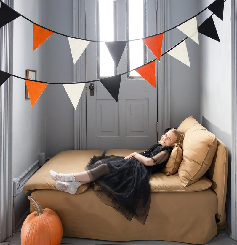 Two strands of felt triangle Halloween banner hanging in a small room above a bed.