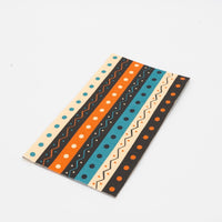 Two folded vintage Halloween guest towels stacked, showing the retro teal-orange-black stripe pattern up close.