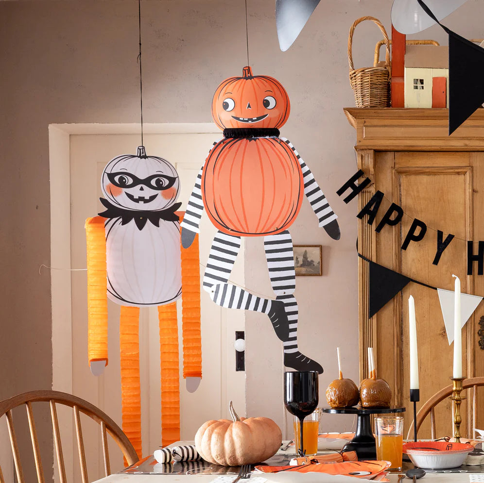 Close view of trio of pumpkin characters posed with “Happy Halloween” garland, showcasing bold Halloween party decor colors.