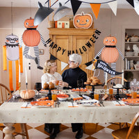 Family table set beneath three 36" hanging pumpkin characters—instant hanging Halloween decorations for parties and photos.