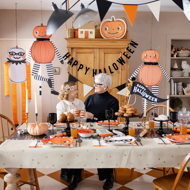 Family table set beneath three 36" hanging pumpkin characters—instant hanging Halloween decorations for parties and photos.