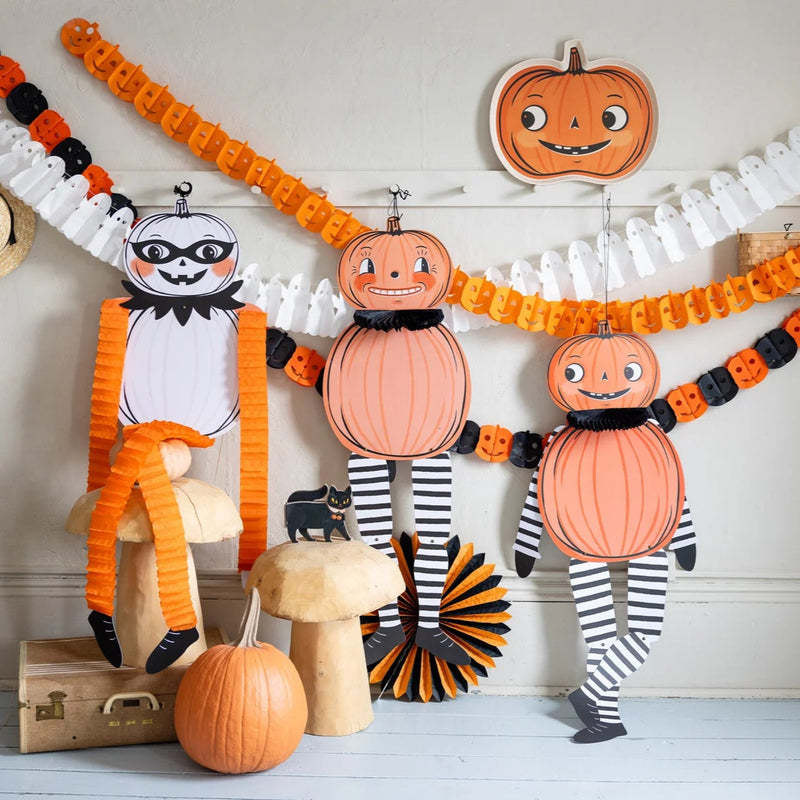 Three coordinated pumpkin characters—one with tissue limbs, two with jointed arms and legs—creating charming paper pumpkin decorations.