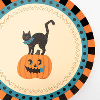 Angled view of the vintage Halloween plate showing the black cat, jack-o'-lantern, and teal-orange-black concentric borders in detail.