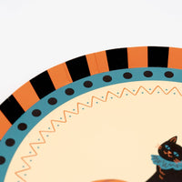 Partial close-up of the vintage Halloween plate showing the orange-black striped and teal-dotted border detail with the cat illustration.