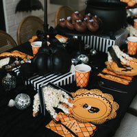 Overhead vintage Halloween place settings with orange and black scalloped plates, Halloween icon plates with bats, pumpkins, and cats, orange polka dot napkins, and a black and white striped runner