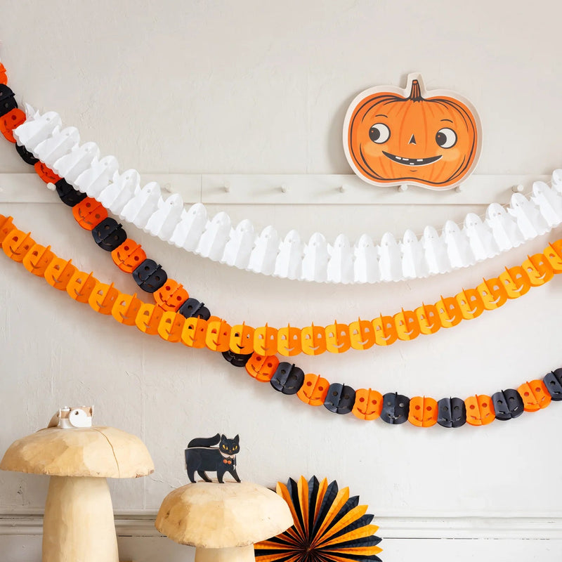 Pumpkin bamboo tray styled as wall decor above Halloween garlands and jointed pumpkin decorations.
