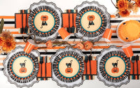 Overhead Halloween table with vintage cat plates, retro striped towels, orange cups, and striped runner across settings.