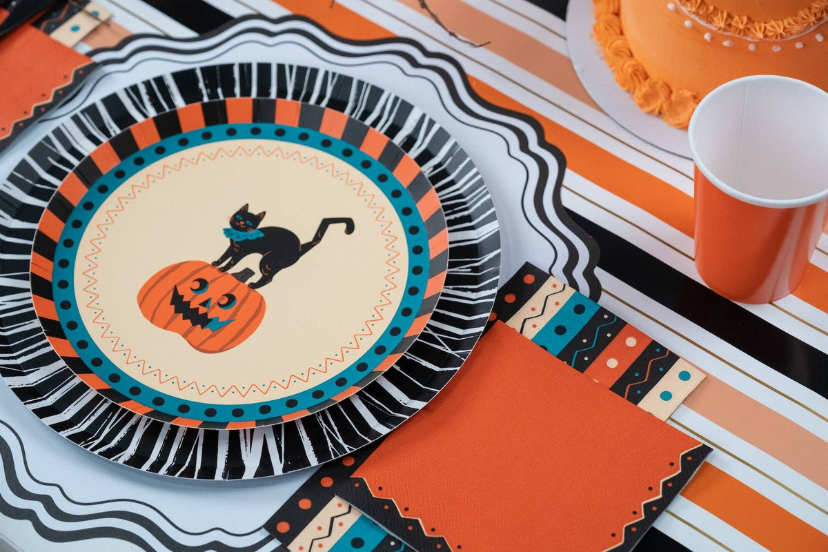 Styled Halloween table with the orange vintage napkins, black rosette plates, orange cups, and striped runner.
