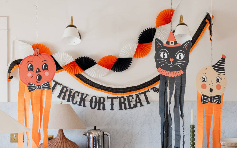 Hanging halloween-themed decorations including a black cat, jack-o'-lantern, and trick-or-treat banner on a wall.