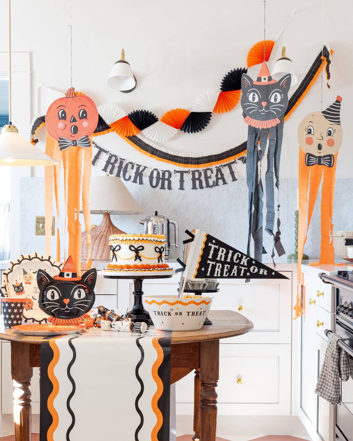 Halloween-themed kitchen with decorations, including a 'Trick or Treat' banner and cat figures.