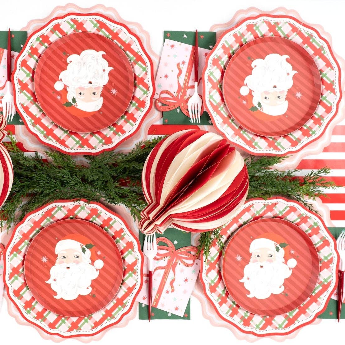 Overhead of four vintage Santa plates on plaid dinner plates with a striped ornament and evergreen.