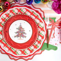 Overhead view of a festive place setting featuring a vintage Christmas tree plate on a plaid charger with the pink present napkin.