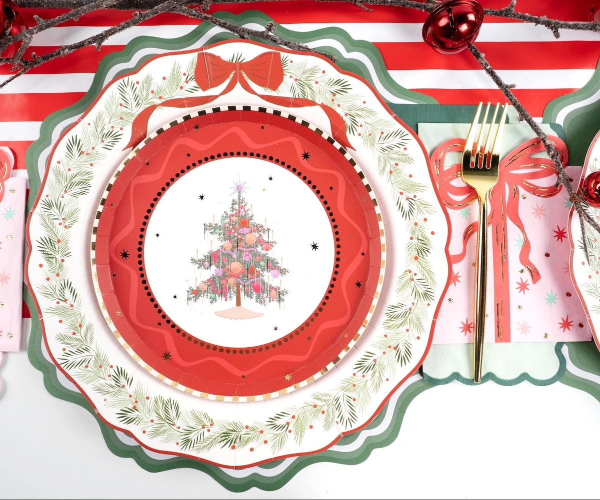 Overhead place setting featuring a vintage Christmas tree plate on a red die-cut scalloped charger with gold flatware.