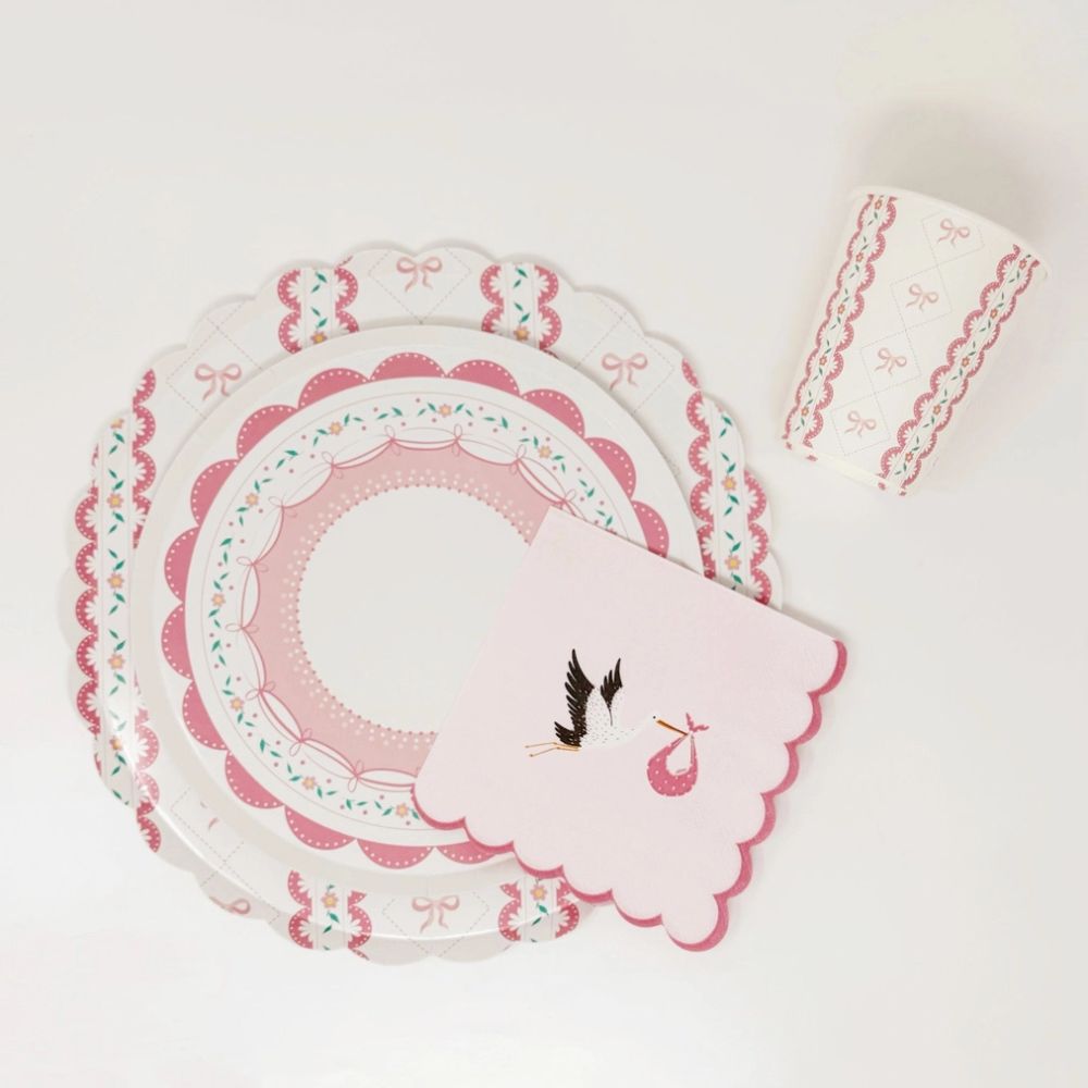 Overhead view of a stork napkin and stacked plates on a white surface