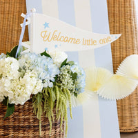 Blue Welcome Little One pennant styled with flowers and baby shower decor