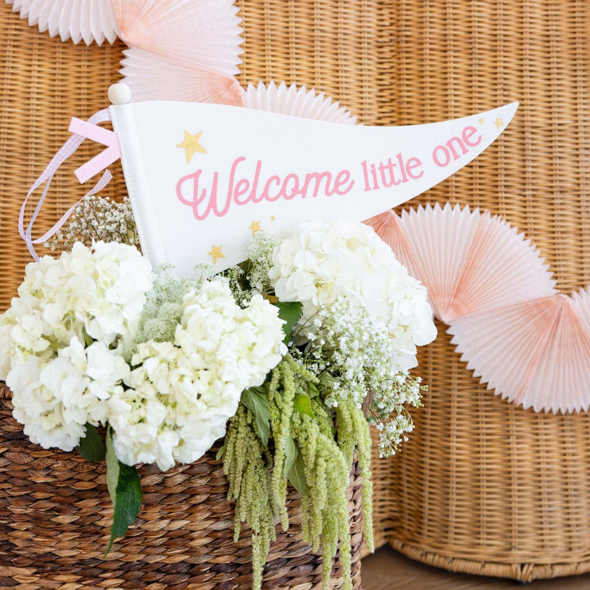 Pink welcome little one pennant displayed in floral basket decor
