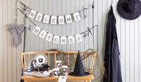 Welcome Witches banner styled in a Halloween setting at the entryway, with black satin bows visible at the ends.