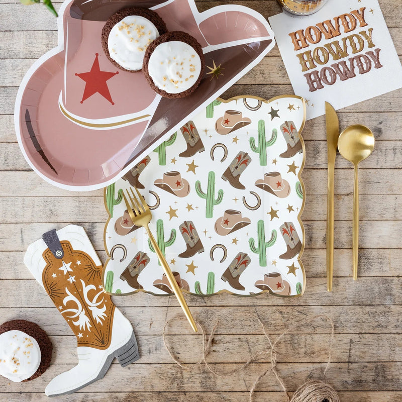 Boot napkin on dessert table with hat plate and cactus print—fun western party decorations.