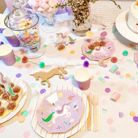 Full party table spread with unicorn plates, treats, and pastel decorations