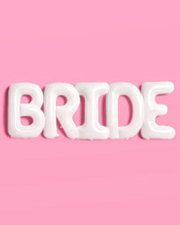 All five white BRIDE letter balloons lined up spelling bride on pink background showing full set and matte mylar finish