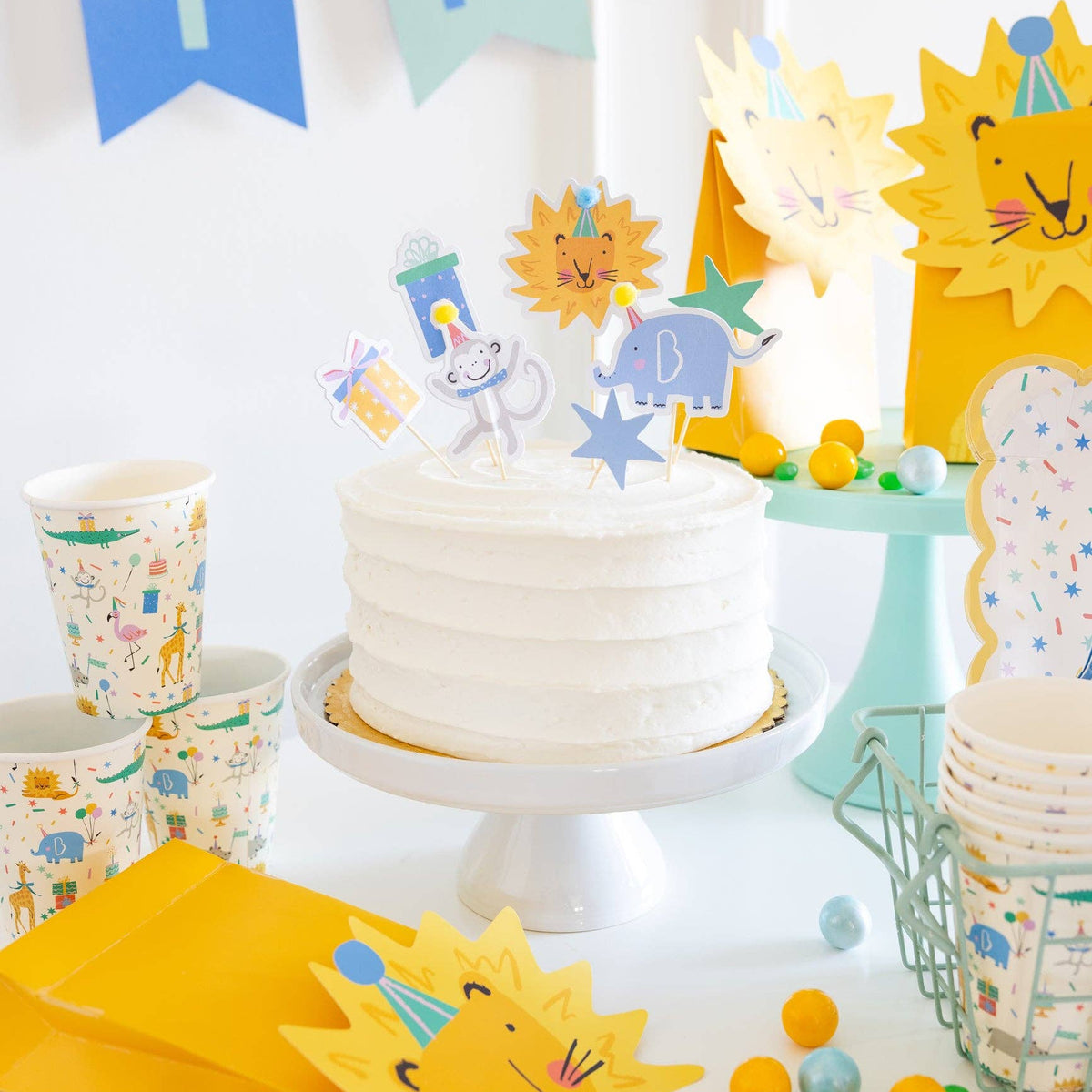 Close-up of animal cupcake toppers on a frosted cake with coordinating safari party decor.