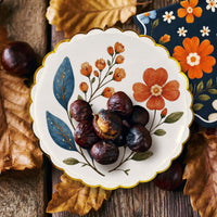 Roasted chestnuts on a wildflower dessert plate among dried oak leaves on a wood table