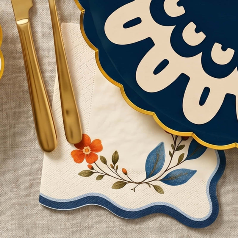 Wavy edge wildflower napkin under gold flatware beside a navy doily plate on linen