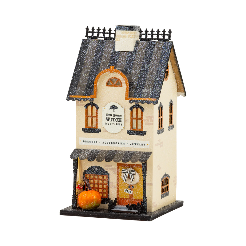 Witch Bootique light up Halloween village house in cream with a striped glitter roof, broom, pumpkin and bow wreath