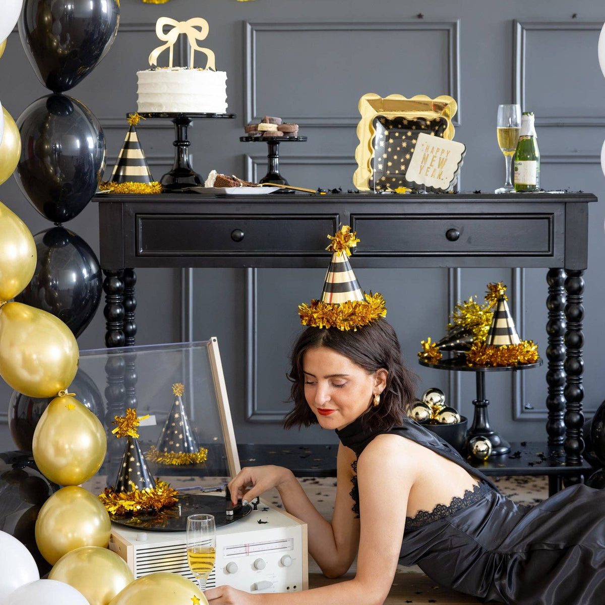Woman wearing black and gold party hat while listening to music