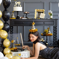Woman wearing black and gold party hat while listening to music