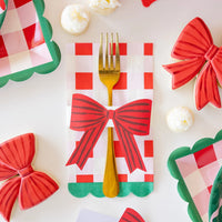 Close-up of gold cutlery tucked into the red plaid napkin, secured by the bow napkin ring set.