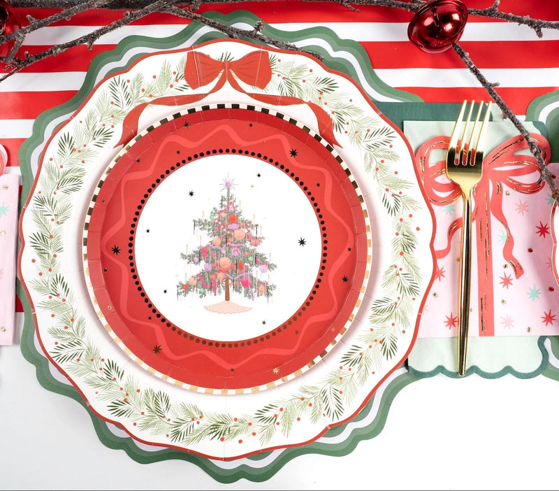 Place setting with a Christmas-tree salad plate on the wreath dinner plate and a green scalloped charger, with a gold fork and a red ornament.