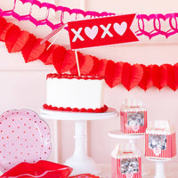 XOXO felt pennant displayed above a cake table with Valentine decorations