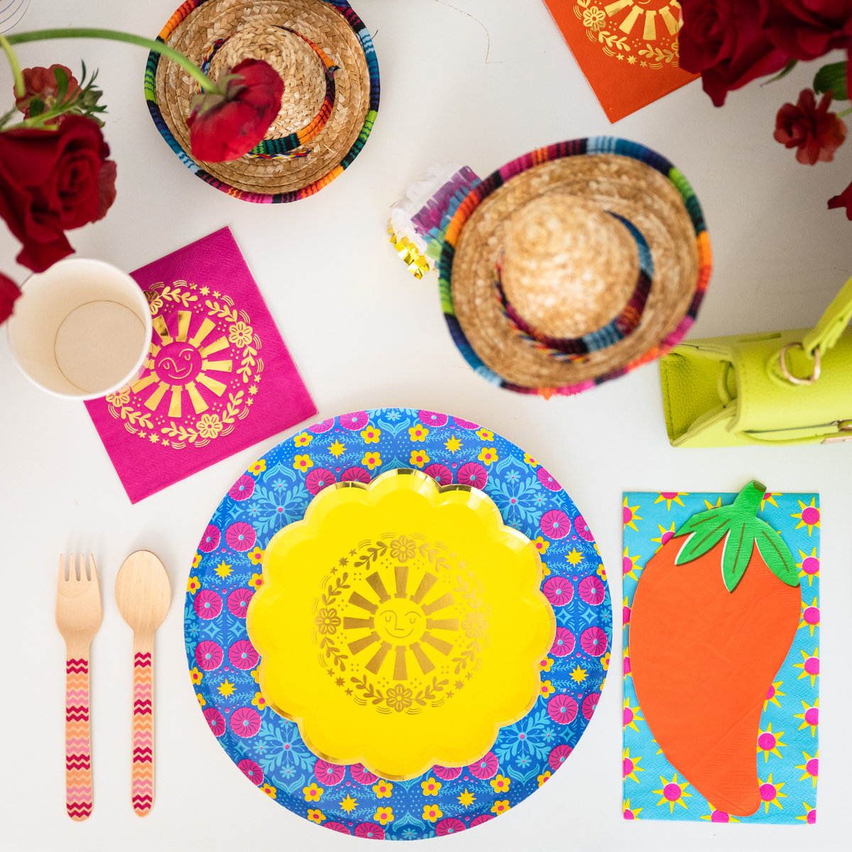 This image shows a yellow sun plate layered on a floral fiesta plate surrounded by sombreros, flowers, and colorful party decor.
