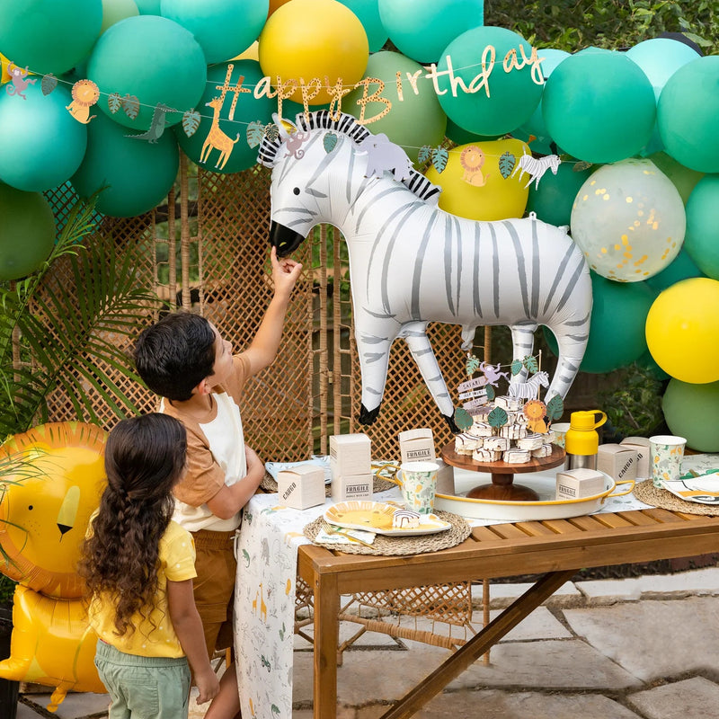 Kids pointing at zebra balloon under green balloon arch—perfect for a zoo birthday party.”
